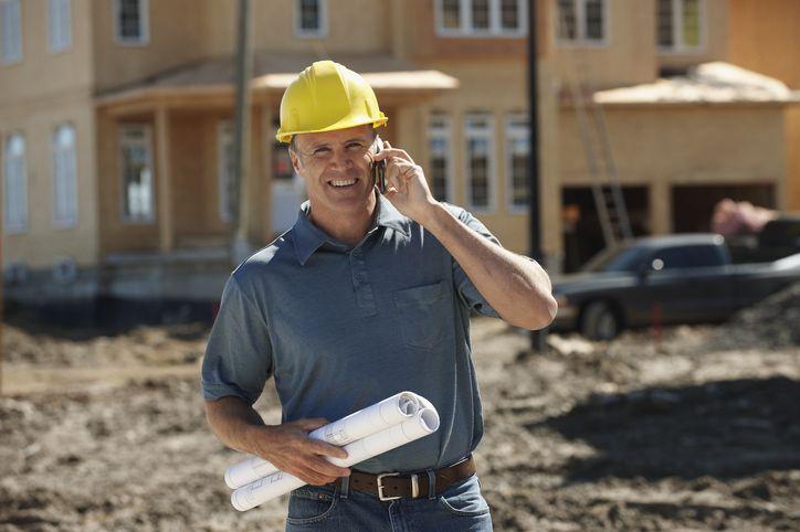 mężczyzna w koszuli i kasku rozmawiający przez telefon